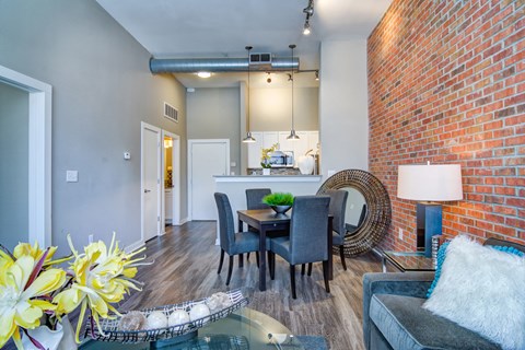 a living room with a dining room table and a brick wall